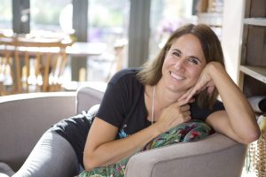 Picture is of author Sarah Sultoon half lying on a sofa with hands up to face 