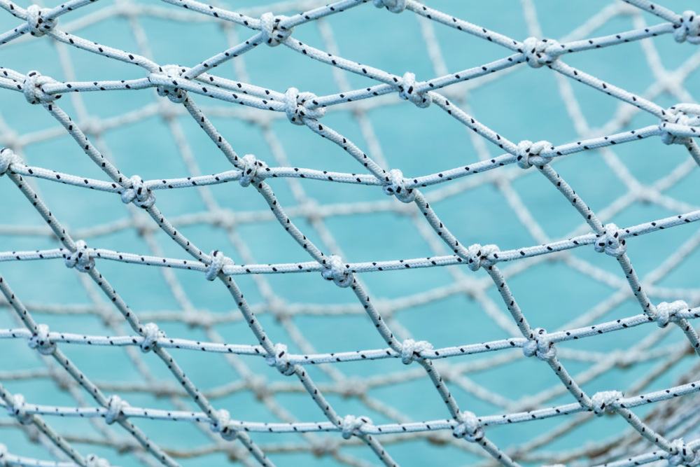 Image: close-up photo of a nylon safety net against a blue background.